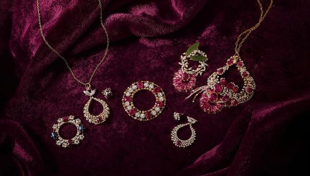 Vintage ruby and crystal brooches with gold teardrop pendants on burgundy velvet backdrop