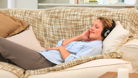 Relaxing at Home: Woman Enjoying Music on Sofa