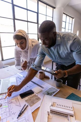Diverse coworkers analyzing architectural plans in modern office