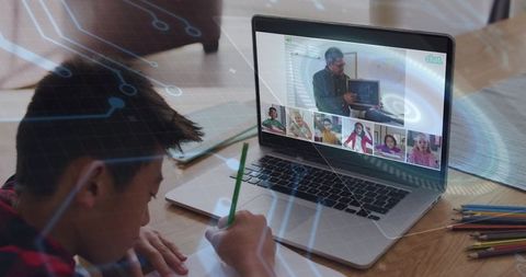 Elementary Student Writing While Participating in Live Remote Classroom on Laptop