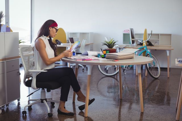 Side view of young businesswoman working while sitting at desk in creative office