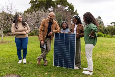African american family exploring solar panel installation with installer in backyard