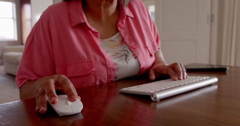 Senior Woman in Pink Shirt Using Keyboard at Home