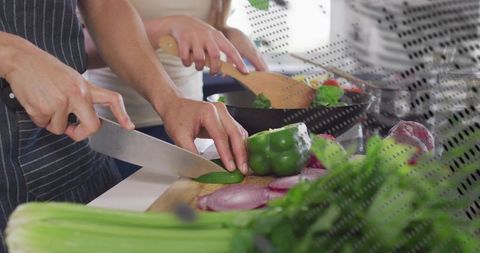 Couple chopping fresh vegetables together on bright kitchen counter for healthy meal prep