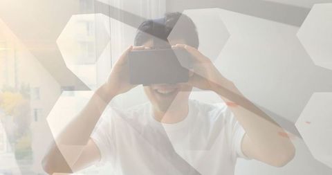 Asian Man Engaged in Virtual Reality Experience Near Sunlit Window