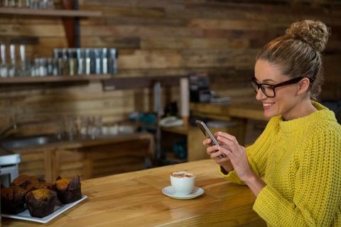 Woman in Stylish Cafe Enjoying Coffee and Smartphone