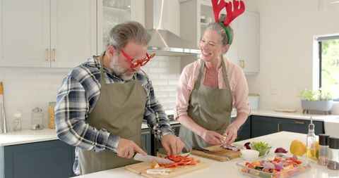 Senior Couple Cooking Together Wearing Antlers in Festive Kitchen