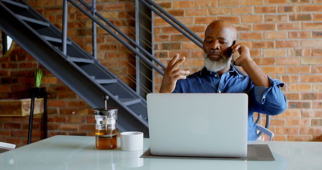 Senior Man Talking on Phone and Working on Laptop in Industrial Office - Download Free Stock Images Pikwizard.com