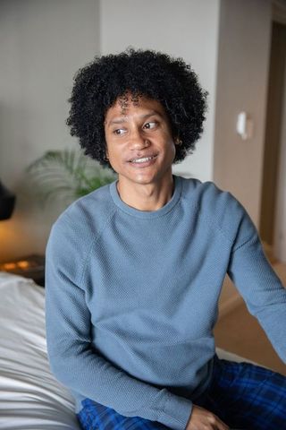 African American Man in Pajamas Relaxing in Cozy Bedroom Environment