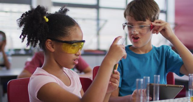 Diverse race schoolchildren wearing protective glasses holding test-tube during chemistry class. children at primary school.