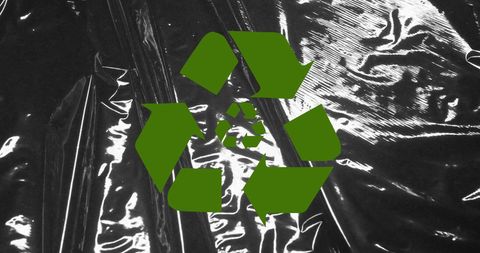 Green recycling symbol on black plastic background