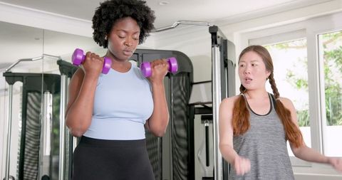 Women Performing Dumbbell Curl in Gym Focused on Fitness Goals