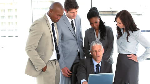 Diverse Business Team in Strategic Discussion Around Laptop