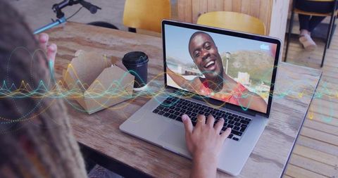 Smiling man appearing on laptop during remote call in cafe, coworking collaboration