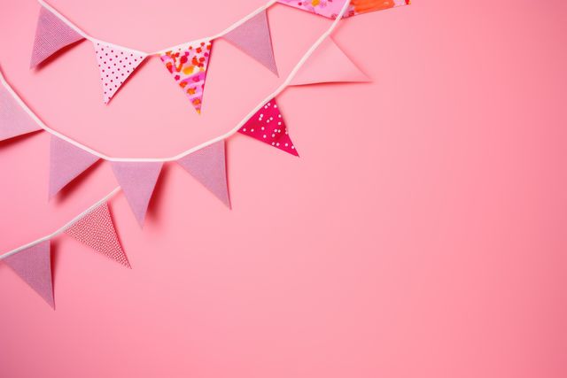 Cheerful image of colorful pink pennant flags against a pink background. Ideal for party invitations, celebrations, festive events, and cheerful party decor designs. Perfect for adding a vibrant touch to marketing materials and social media posts.