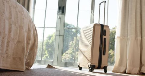 Stylish cream suitcase in sunlit minimalist interior