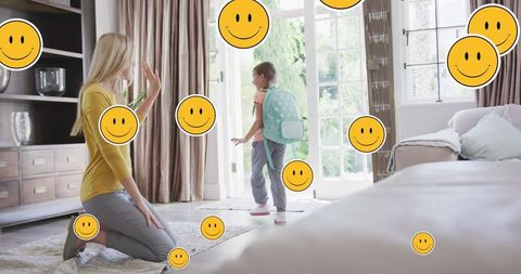 Mother preparing daughter for school with digital smiley faces
