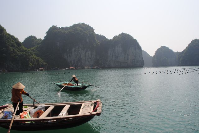 Fishermen rowing boats on tranquil waters in picturesque bay cliffs - Download Free Stock Photos Pikwizard.com