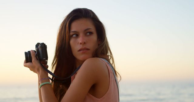 Young Woman Holding Camera with Beach Background - Download Free Stock Images Pikwizard.com