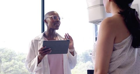 Clinician explaining breast imaging procedure to patient while holding tablet
