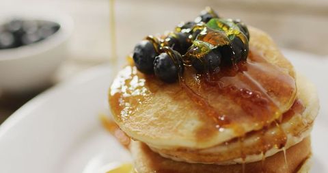 Delicious pancakes stacked with blueberries drizzled in honey