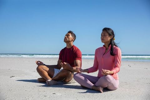 Diverse Couple Meditating on Sandy Beach Enhancing Wellness and Harmony