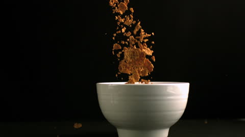 Brown Cereals Pouring Into White Bowl in Slow Motion