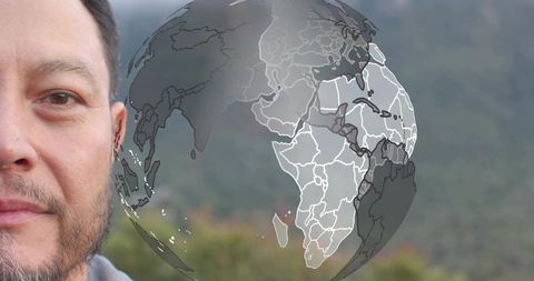 Facing camera man with translucent globe overlay over blurred mountain landscape