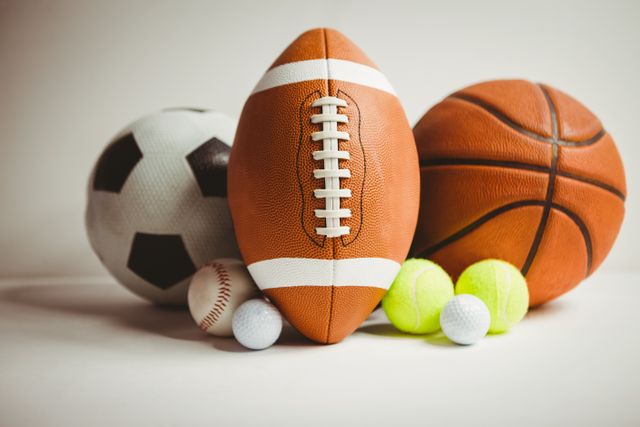 Various sports balls including a football, soccer ball, basketball, tennis balls, baseball, and golf balls arranged on a white background. Ideal for use in sports-related content, advertisements for sporting goods, or educational materials about different sports.