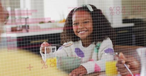 Smiling girl scooping cereal at breakfast with orange juice in sunny family kitchen at table