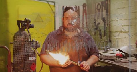 Artisan welding metal worker using flamethrower in industrial workshop