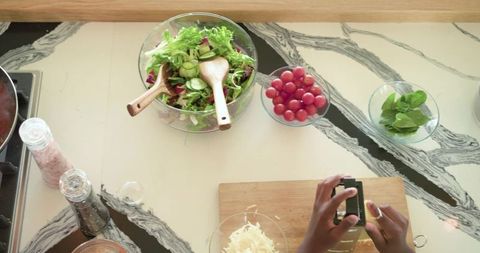 African american hands grating cheese over cutting board making salad with tomatoes and basil