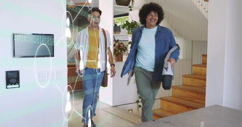 Two young men walking into modern smart home entryway carrying portable speaker