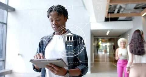 Young man tapping tablet for digital banking with futuristic bank icon overlay
