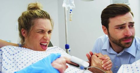 Expectant woman pushing through labor while partner offering support in hospital delivery