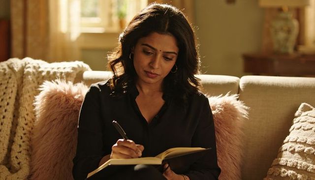 Woman writing in notebook on cozy living room sofa, evening journaling and reflection