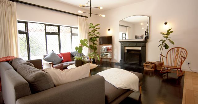 Bright living room featuring modern and stylish furniture, cozy fireplace, large windows for natural light, and minimalistic decor with green plants. Ideal for home decor inspiration, interior design projects, real estate listings, and lifestyle blogs.