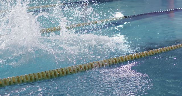 Swimmer in action at a pool during a competitive race. The focus on the water's splash emphasizes the intensity of the swim meet.