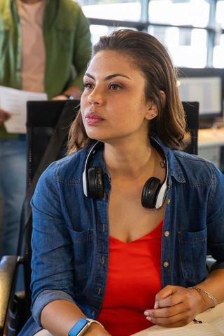 Professional woman checking smartwatch in modern open-plan office wearing headphones