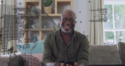 Smiling senior man scrolling smartphone on couch at home, cozy tech relaxation lifestyle