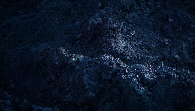 Midnight glowing gravel mound with blue-lit sparkling crystals and jagged rocky texture