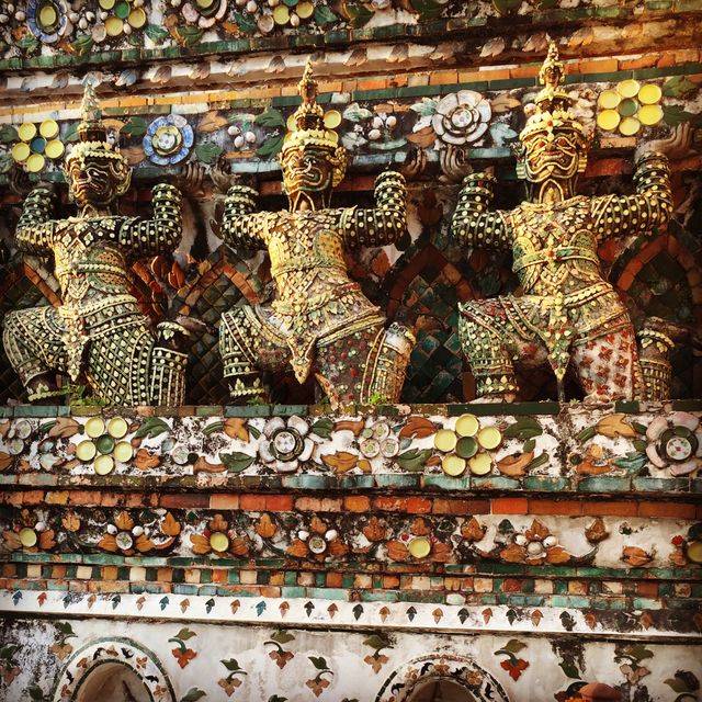 Motionless guardians adorn the facade of an ancient temple in Thailand. Intricately decorated with vibrant colors and intricate designs, these sculptures reflect the rich cultural heritage and traditional art of the region. Ideal for use in travel magazines, cultural event promotions, and educational material on Asian architecture.
