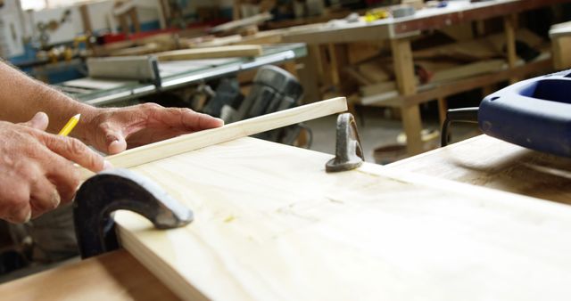 Focus on carpenter drawing a wood plank in workshop