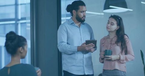 Diverse Colleagues Collaborating Over Tablet in Modern Office