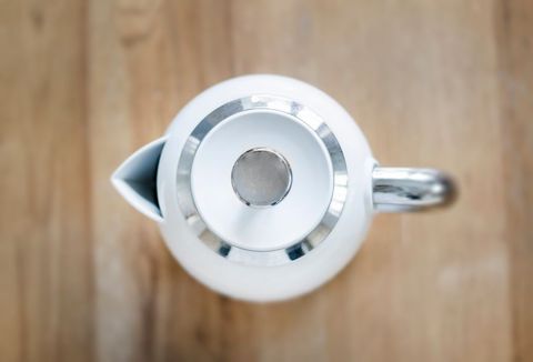 Top view of modern white tea kettle on wooden surface