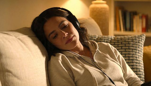 Woman relaxing on sofa listening to music with headphones in cozy living room