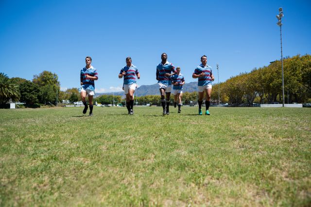 Confident rugby team running at field on sunny day