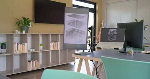 Modern design studio workspace with dual monitors, laptop and architectural renderings