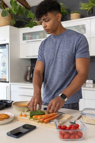 African american man preparing fresh vegetables on modern kitchen island