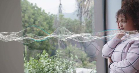 Contemplative woman gazing out window with translucent digital waveform overlay